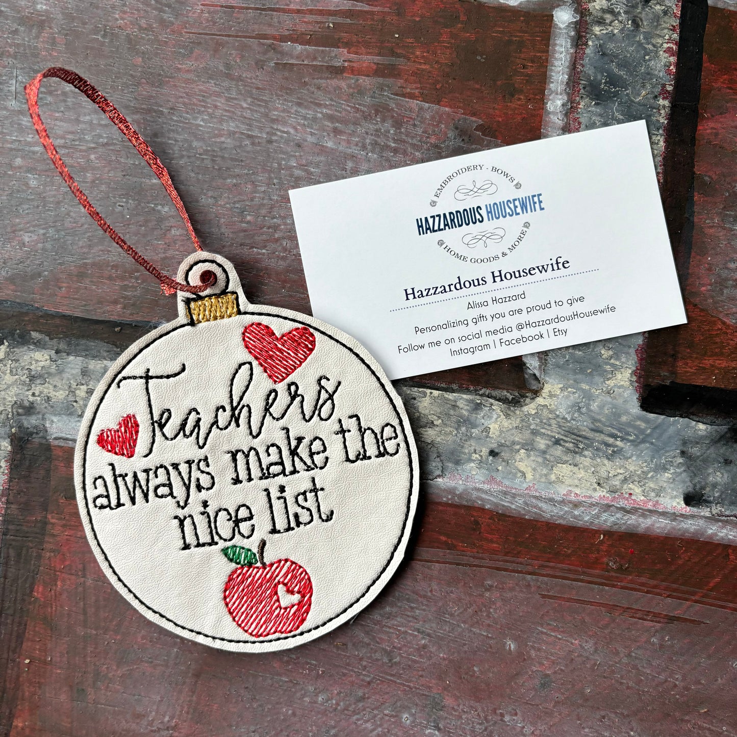 Decorative ornament with 'Teachers always make the nice list' text and an apple design, placed on a rustic wooden surface.