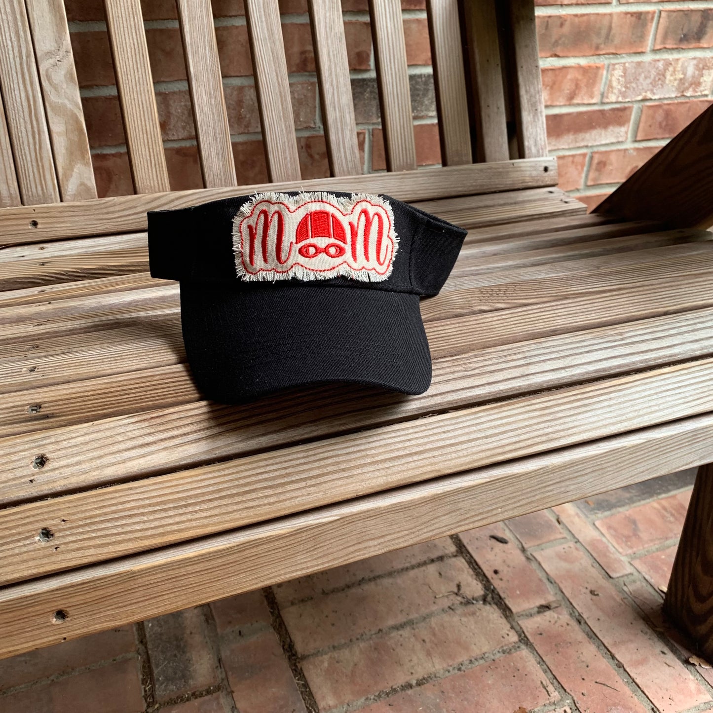 Black cap with a red and white logo on a wooden bench.