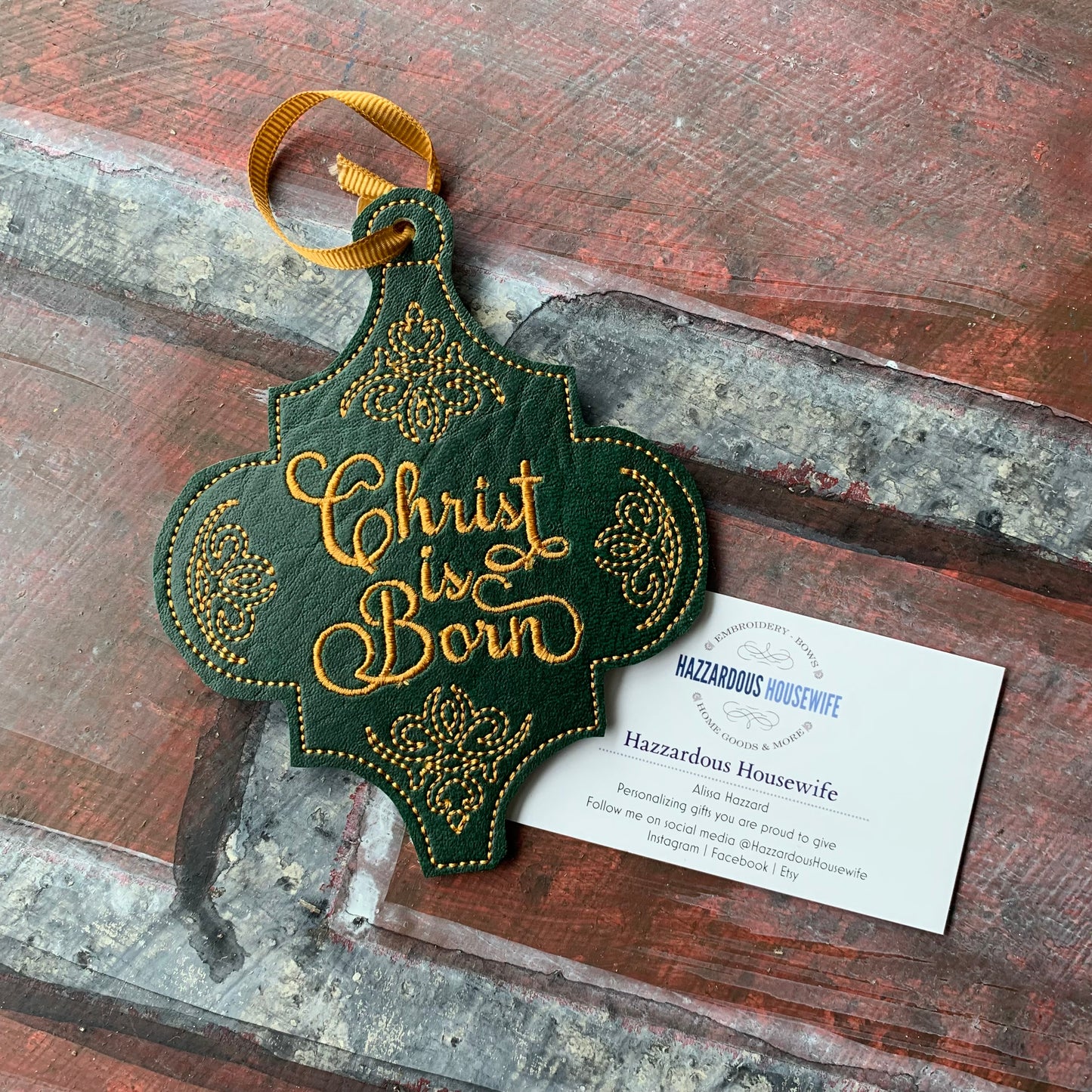 Decorative Christmas ornament with 'Christ Is Born' text on a rustic wooden surface.