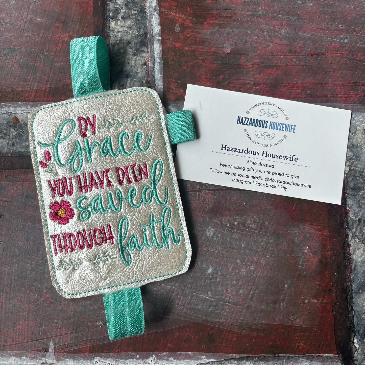 Embroidered book band with motivational quote on a wooden surface with a business card.