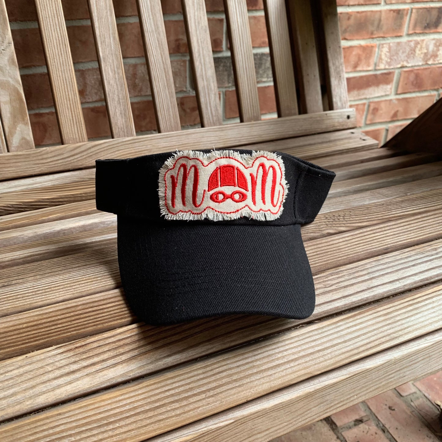Black cap with red and cream logo on a wooden bench