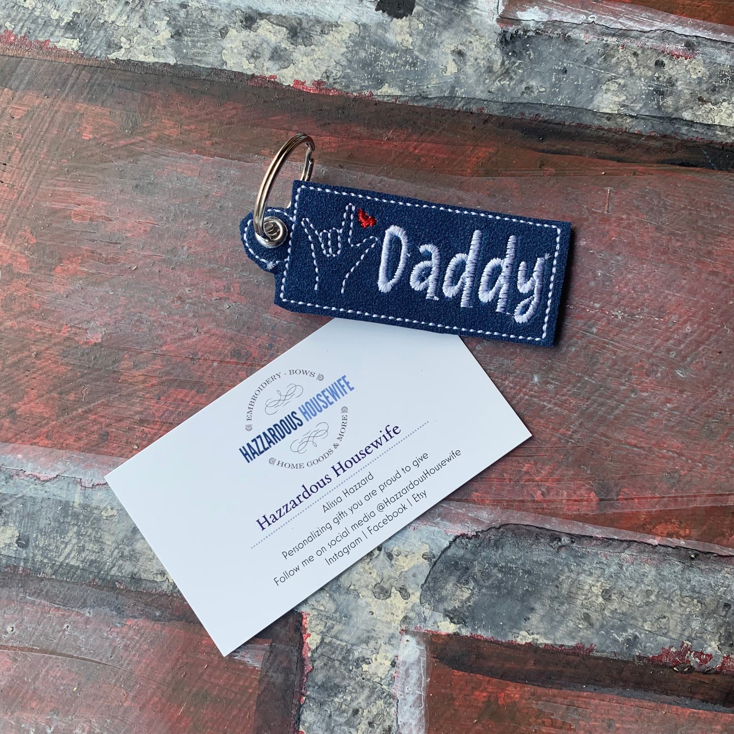 Navy blue keychain with 'Daddy' text on a rustic wooden surface