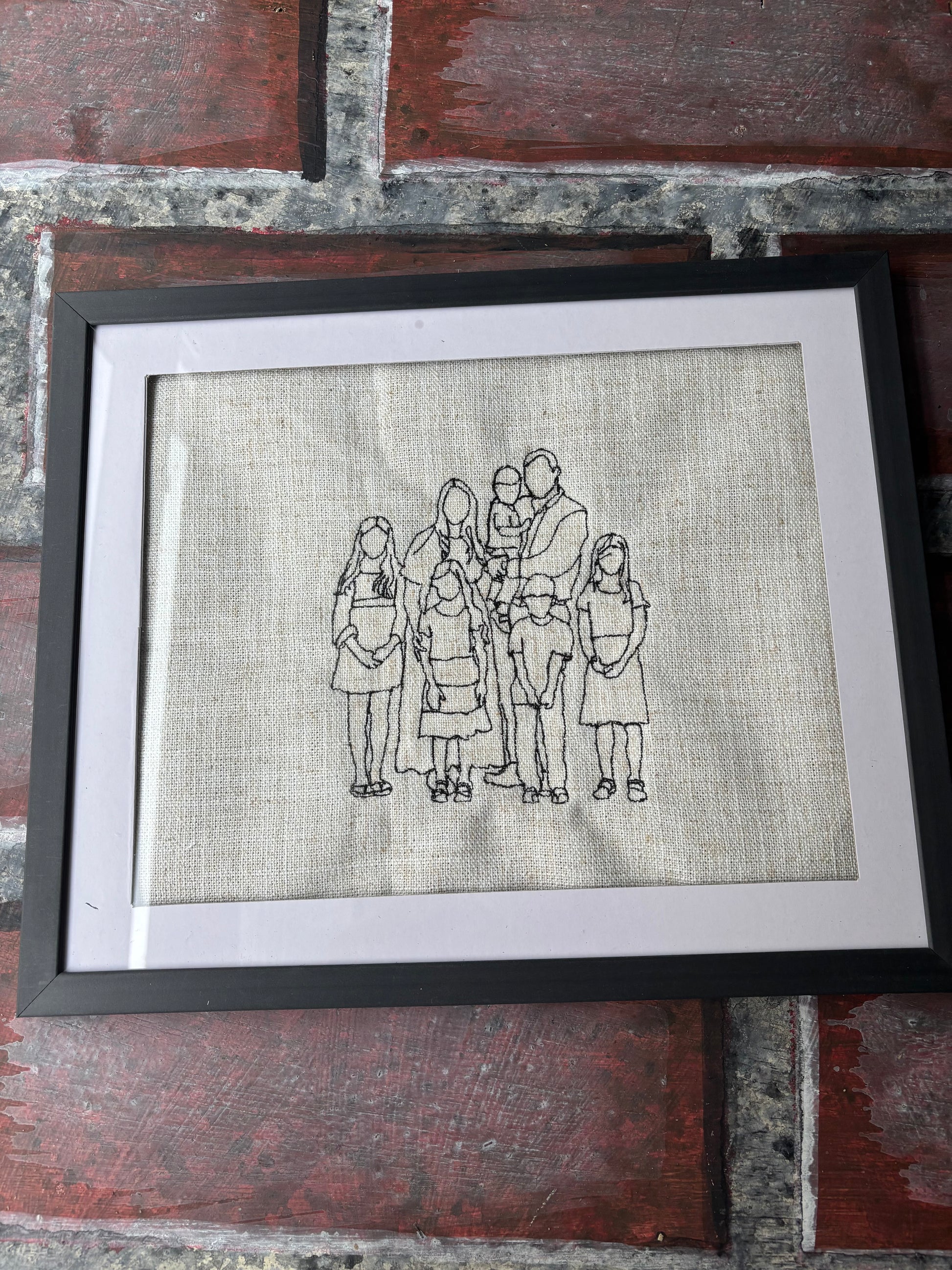 Framed black and white illustration of a family on a textured fabric background