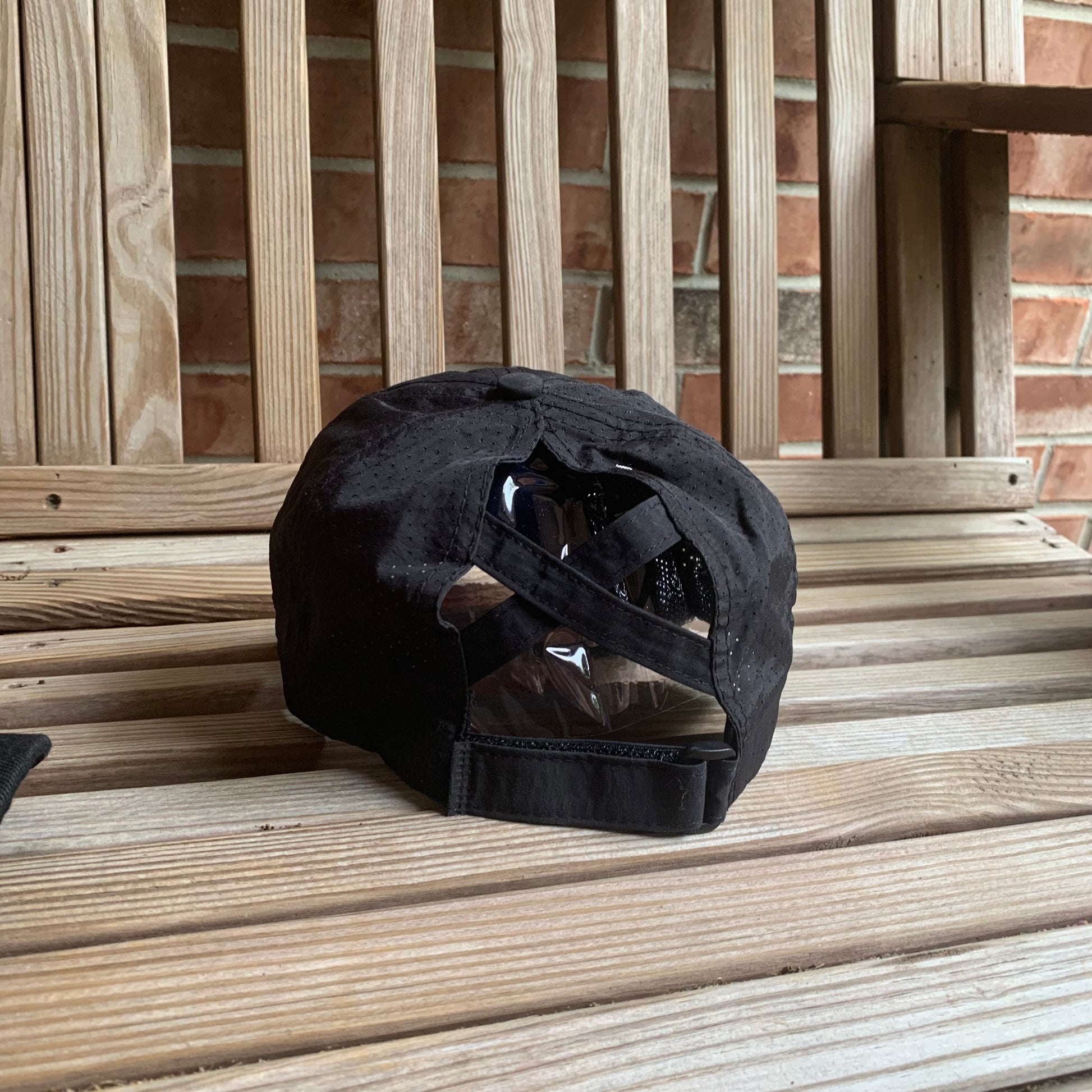 Black hat with ponytail slots on a wooden surface