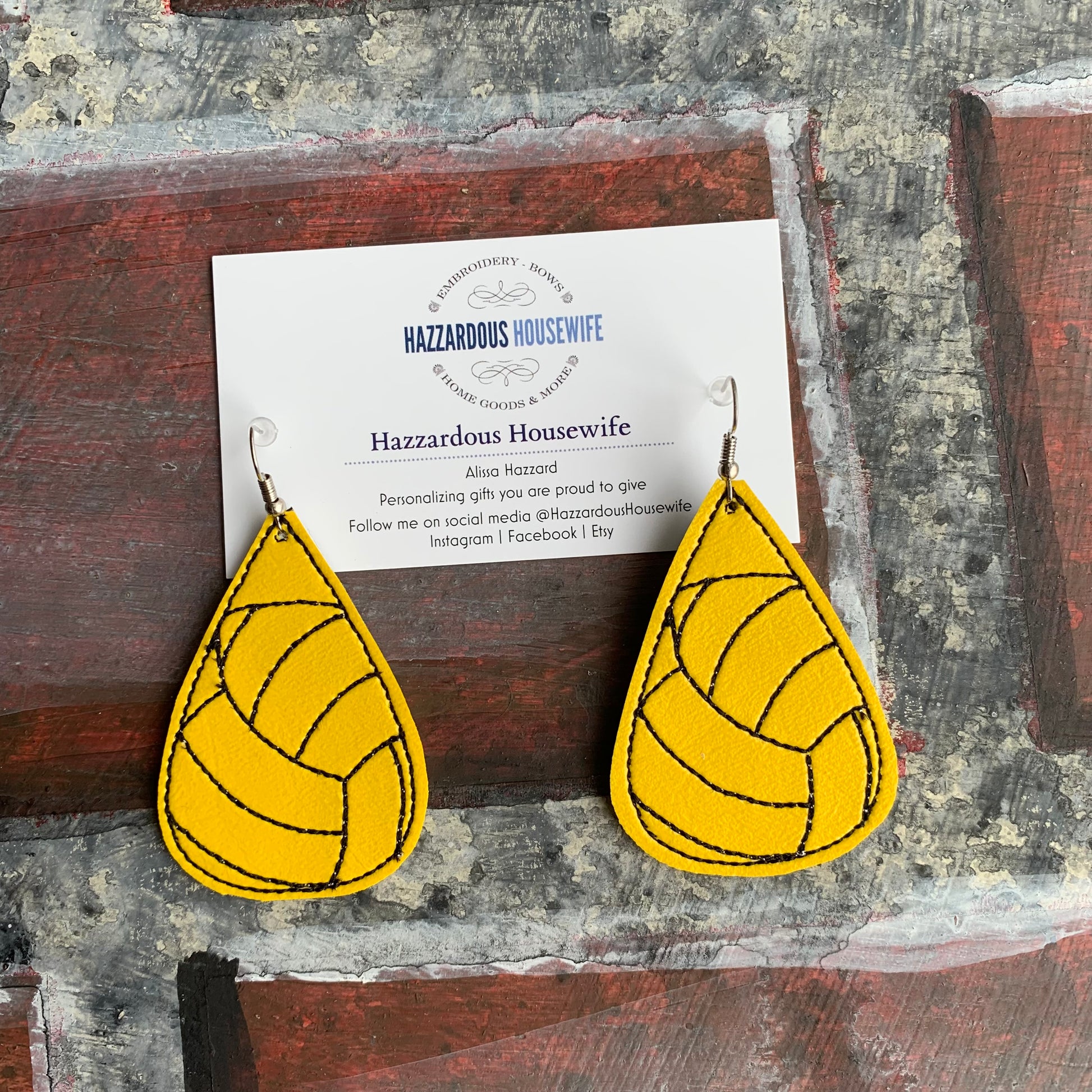 Yellow teardrop-shaped earrings on a card with 'Hazzardous Housewife' branding.