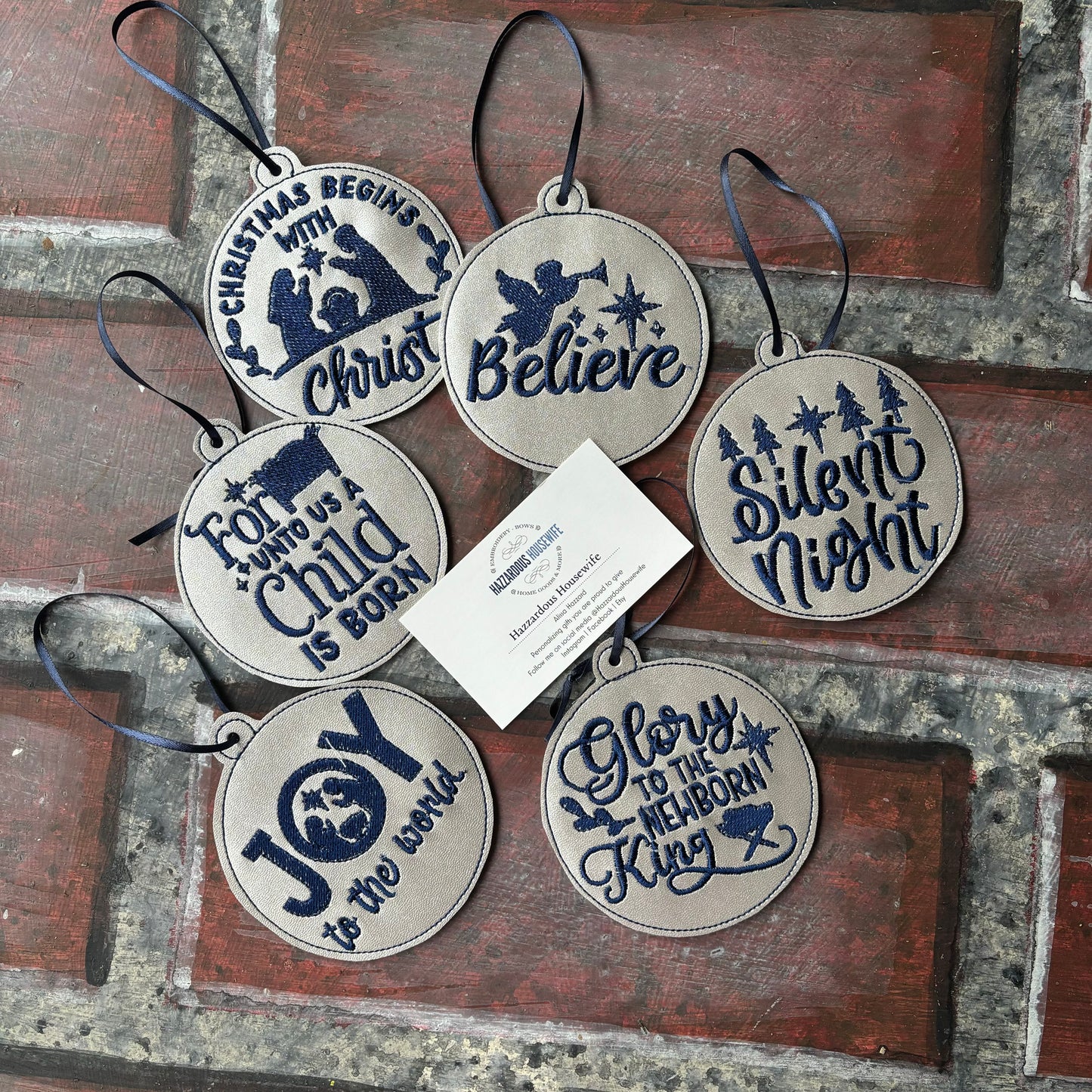 Set of Christmas-themed decorative silver and blue ornaments with text on a rustic wooden surface.
