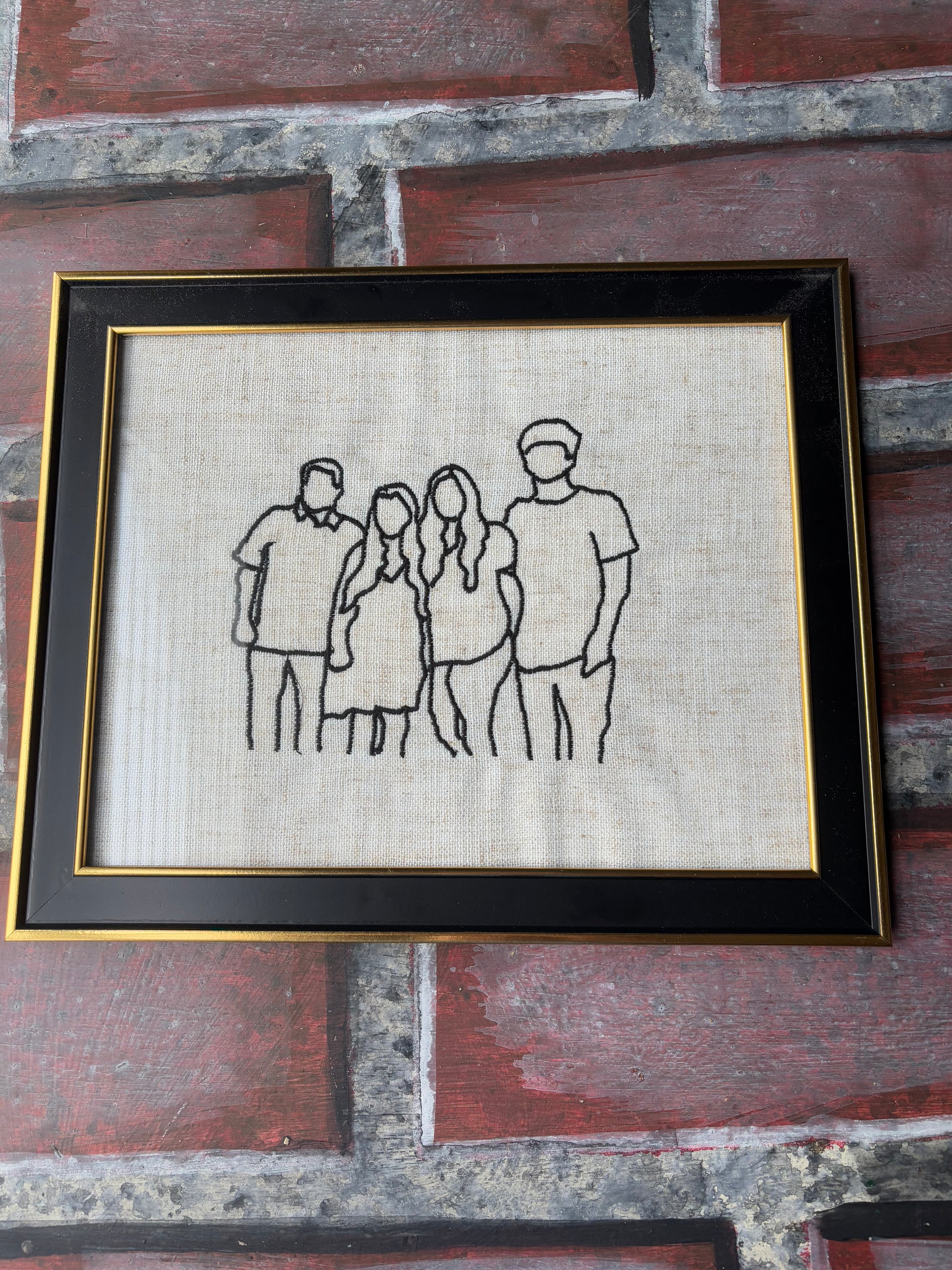 Framed black and white line drawing of a family on a textured wall.
