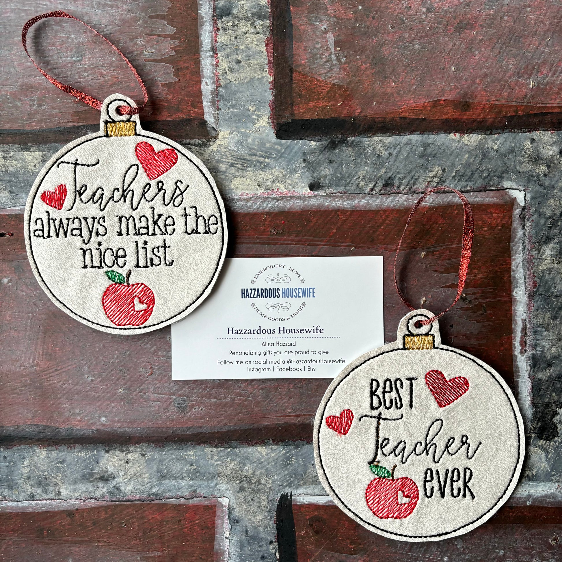 Two embroidered ornaments with text and red hearts on a rustic wooden background.
