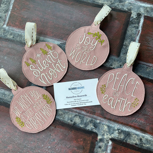 Set of round pink ornaments with text and a business card on a rustic wooden surface