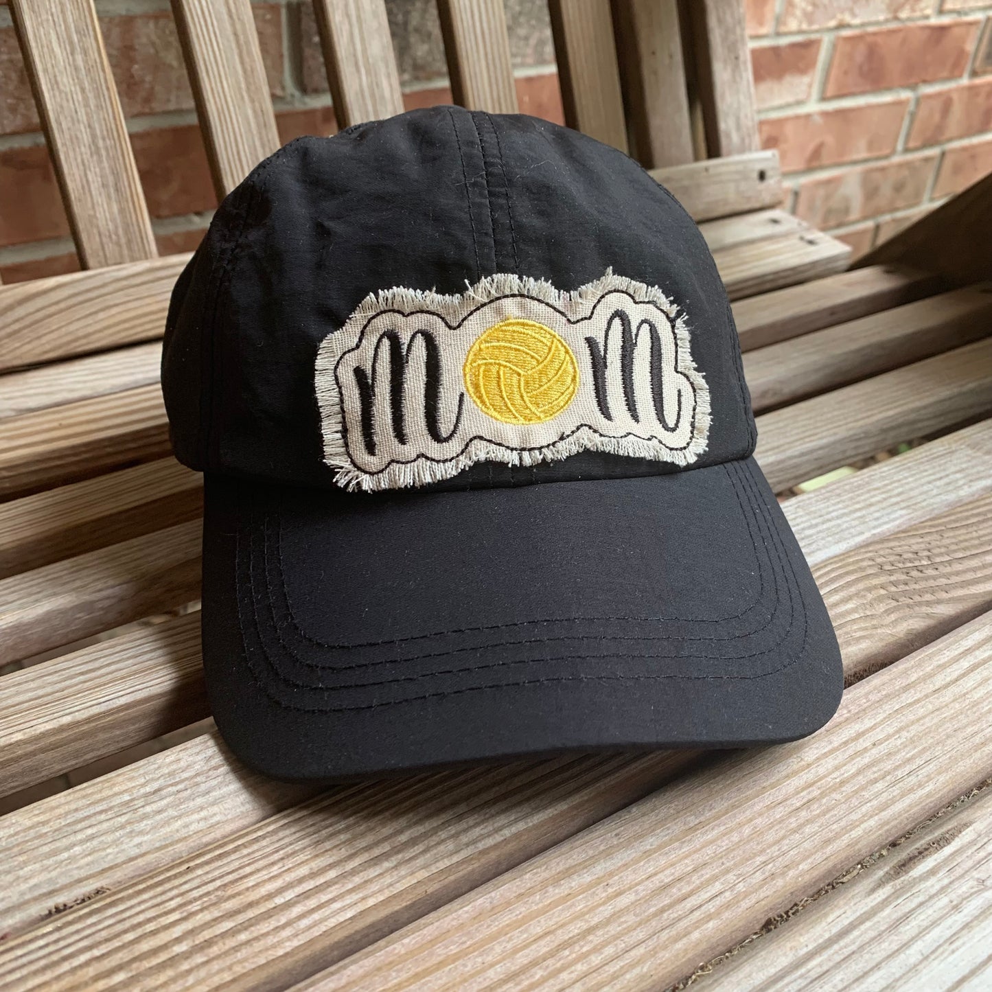 Black cap with a yellow and white logo on a wooden surface