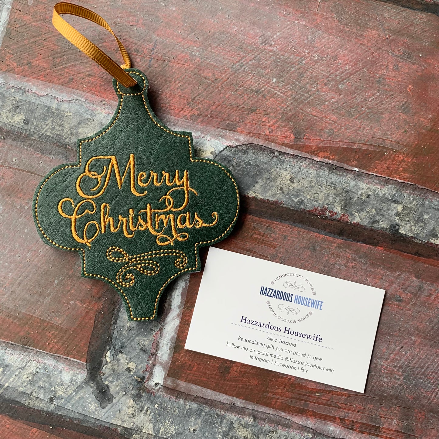 Decorative 'Merry Christmas' ornament with a business card on a wooden surface