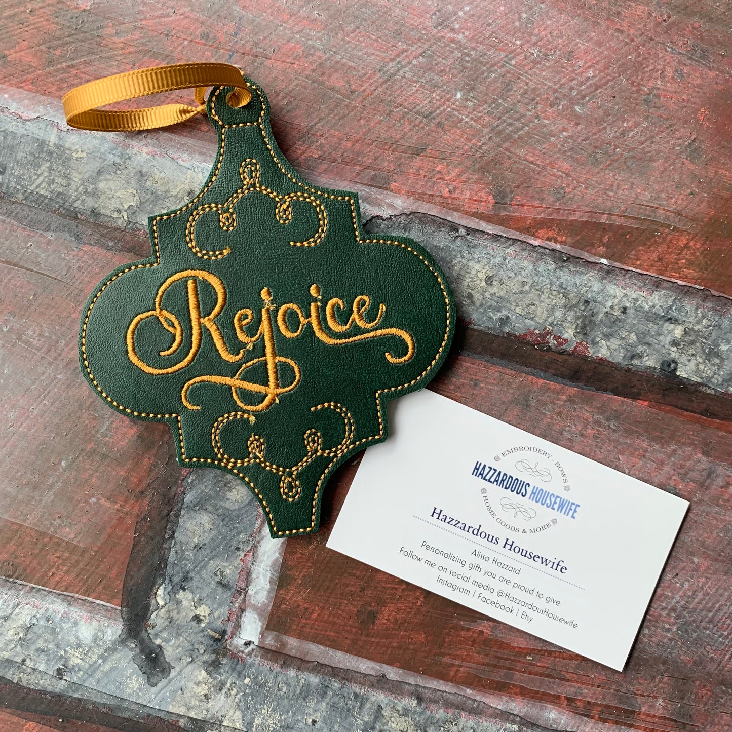 Decorative green ornament with 'Rejoice' text on a rustic wooden surface