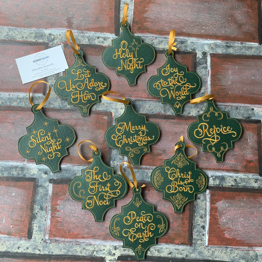 Set of green and gold Christmas ornaments with festive phrases on a rustic wooden background.