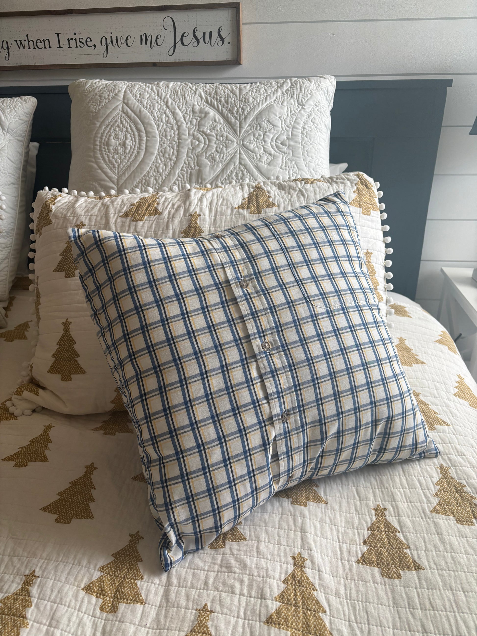 Plaid Memory pillow on a bed with a decorative headboard and tree-patterned bedding.